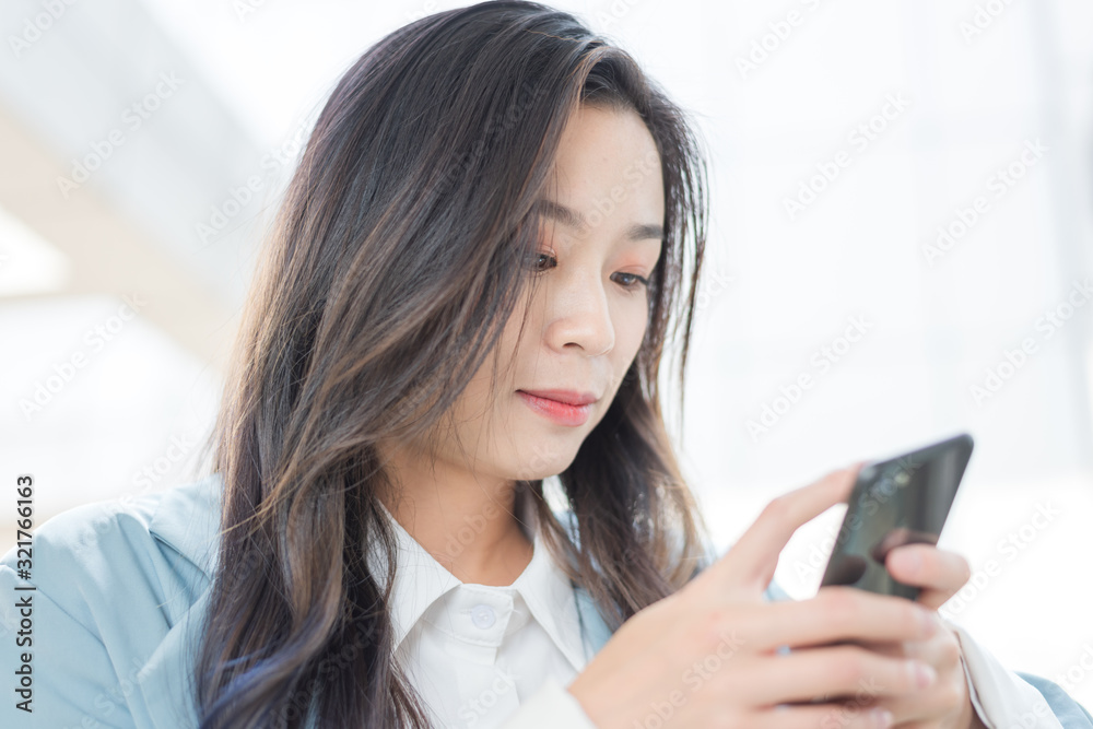 Business ladies use mobile phones in the corridor of office building