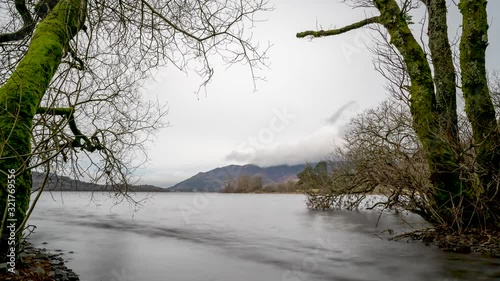 4K. Amazing time lapse of a winter landscape, made up by a lake, surrounded by trees,  at the Lake District, England. photo