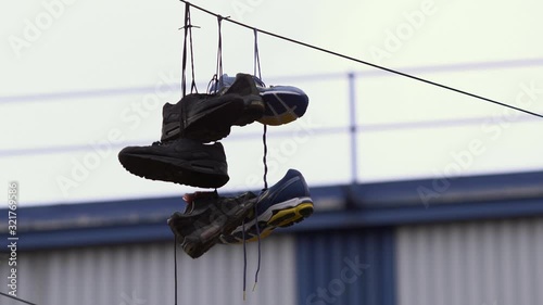 Close up of shoes tied at the laces and hanging from a telephone wire photo