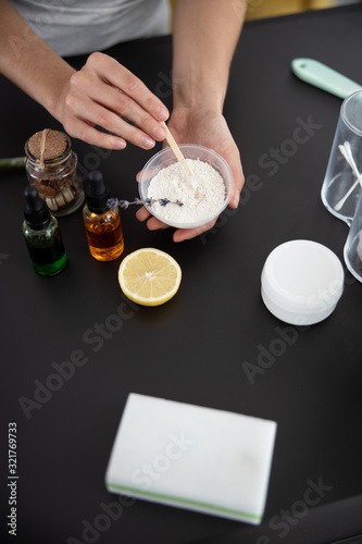 Young lady preparing cosmetic clay for mask