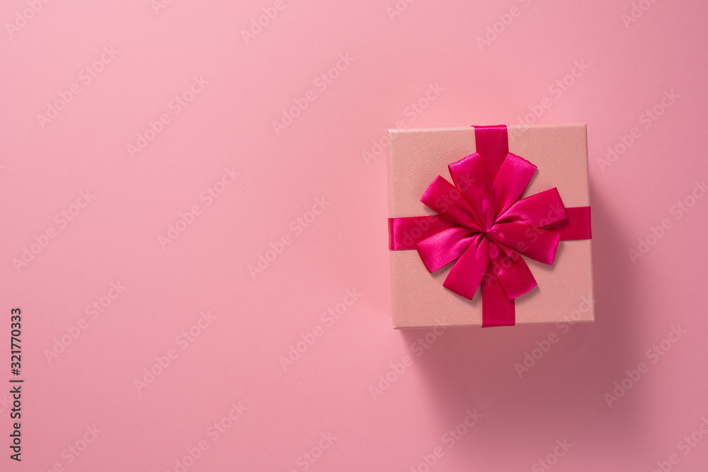Valentine's Day celebration concept. A nice gift from a loved one. Box with a bow on a delicate pink background. Copy space. Flat lay. Close-up.