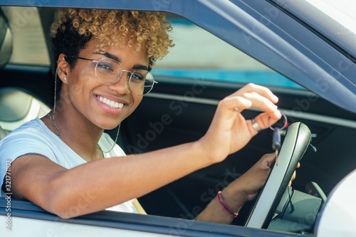 cheerful young african american latin girl showing her new car key at dealership