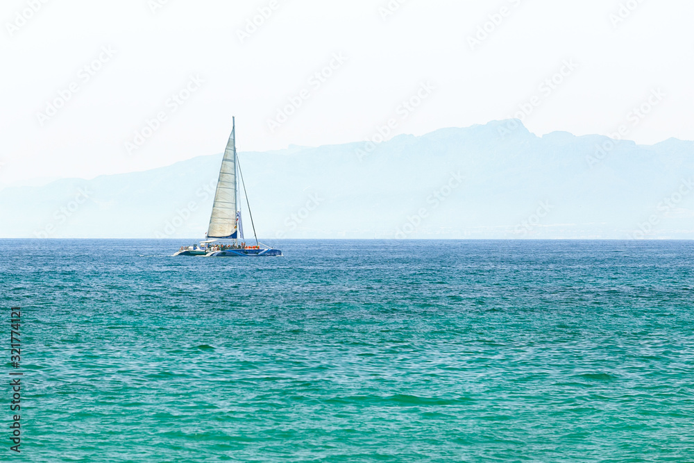 Obraz premium Sailboat in the sea in the sunlight over beautiful mountains background. Freedom concept.