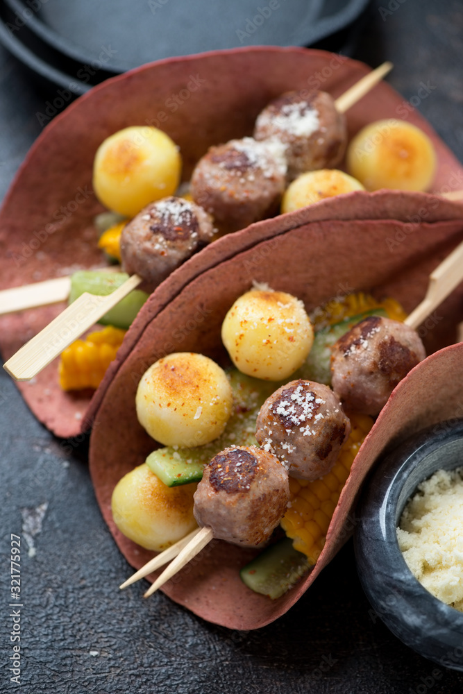 Tortilla wraps with roasted meatballs on wooden skewers, potato balls, sweet corn and cucumber, close-up, selective focus Tortilla wraps with roasted meatballs on wooden skewers, potato balls, sweet corn and cucumber, close-up, selective focus