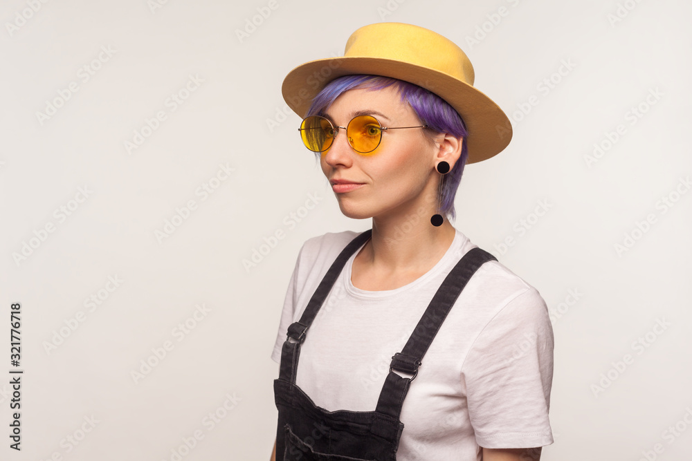 Fashion look. Half-turned portrait of glamour cute hipster girl with violet hair in sunglasses and hat looking aside, bright stylish appearance, clean skin. isolated on white background, studio shot Fashion look. Half-turned portrait of glamour cute hipster girl with violet hair in sunglasses and hat looking aside, bright stylish appearance, clean skin. isolated on white background, studio shot