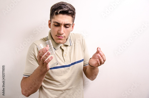 Young man with a glass of water and a pill in his hand photo