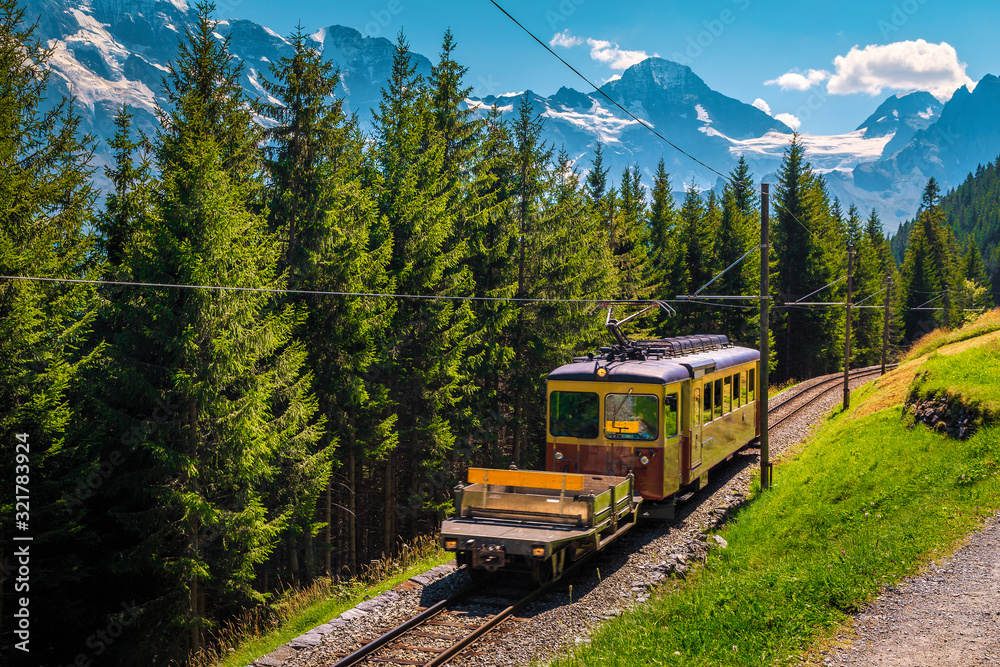 Naklejka premium Electric tourist train and snowy mountains, Murren, Bernese Oberland, Switzerland