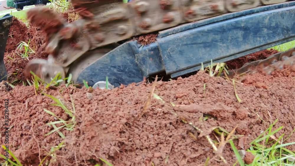Closeup shot of trenching machine digging a trench into the ground for new irrigation system pipes