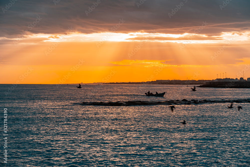 Sunset on the coast of Bari, silhouette of small fishing boats on the Adriatic Sea.