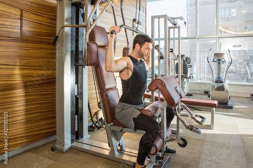 Foto Handsome man exercising on lat pull down machine