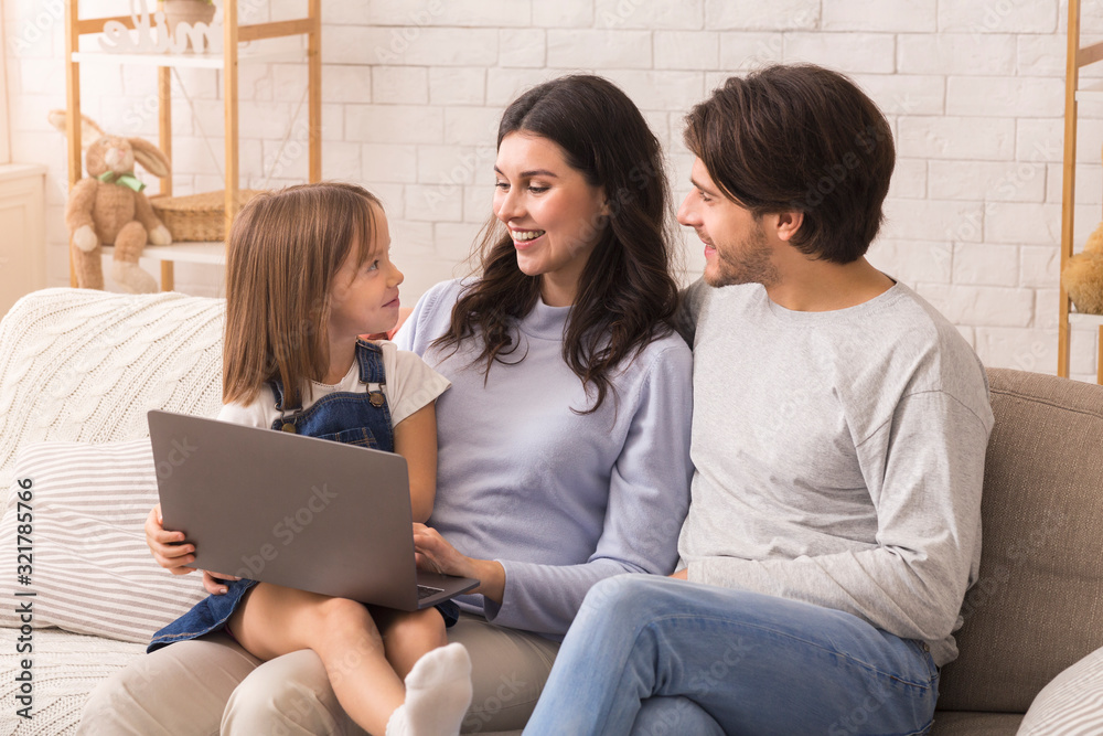 Portrait of young parents and their little daughter using laptop together Portrait of young parents and their little daughter using laptop together