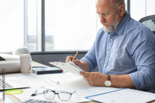 Good looking mature architect drawing something while working in the office.
