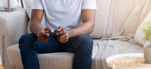 African guy playing video games with joystick at home