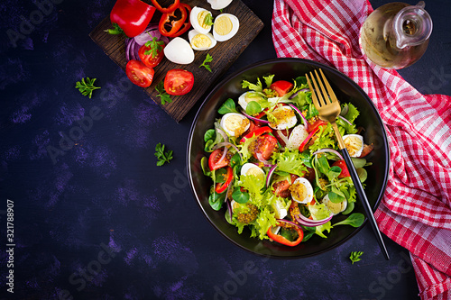 Fresh salad with vegetables tomatoes, red onions, lettuce and quail eggs. Healthy food and diet concept. Vegetarian food. Top view, overhead