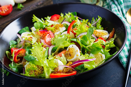 Fresh salad with vegetables tomatoes, red onions, lettuce and quail eggs. Healthy food and diet concept. Vegetarian food.