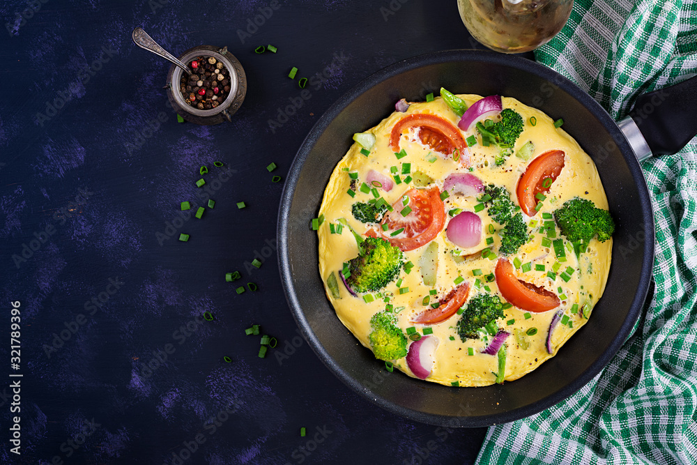 Omelette with broccoli, tomatoes and red onions in iron skillet. Italian frittata with vegetables. Top view, overhead Omelette with broccoli, tomatoes and red onions in iron skillet. Italian frittata with vegetables. Top view, overhead