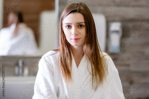 Portrait of a beautiful young positive smiling baucasian woman lying on couch waiting for a therapeutic massage in spa salon. Concept of rejuvenation and relaxation