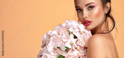 Beautiful white girl with flowers. Stunning brunette girl with big bouquet  o...