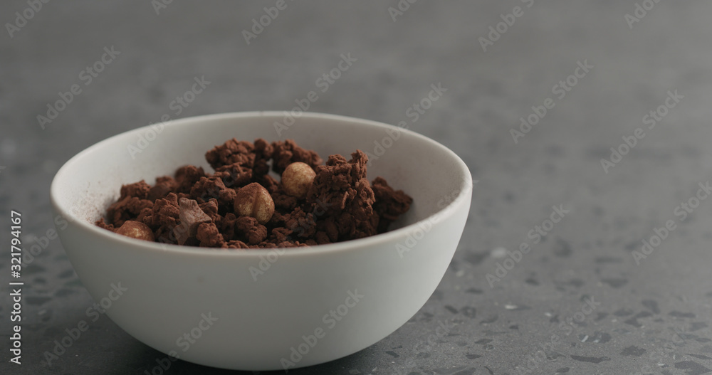 chocolate granola with nuts in white bowl on terrazzo surface chocolate granola with nuts in white bowl on terrazzo surface