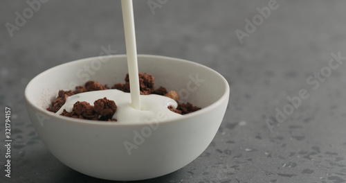yogurt pour over chocolate granola in white bowl on terrazzo surface