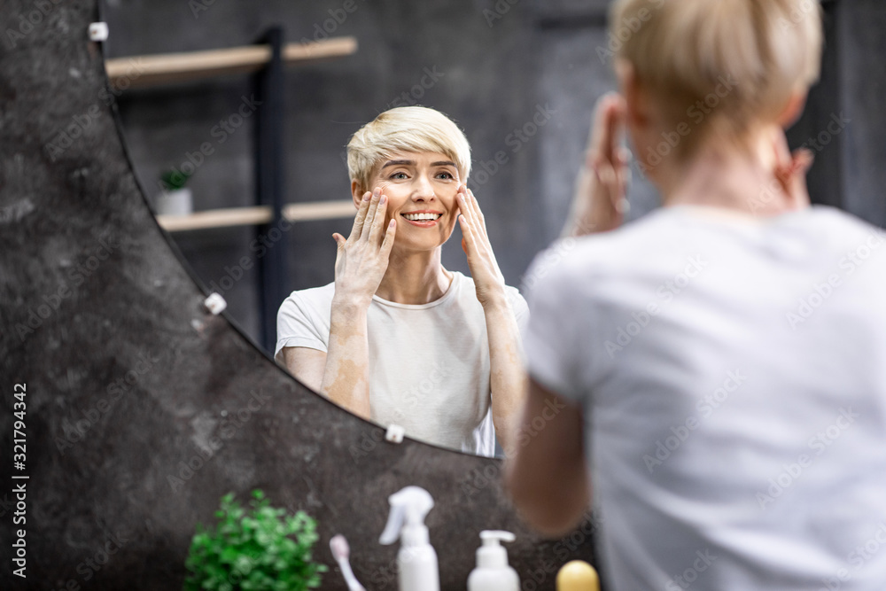Lady Touching Face Skin Looking In Mirror In Bathroom Lady Touching Face Skin Looking In Mirror In Bathroom