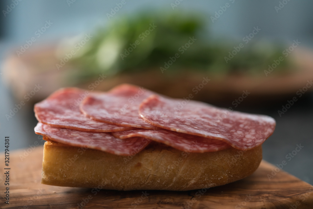 Toasted ciabatta with salami sausage on olive board