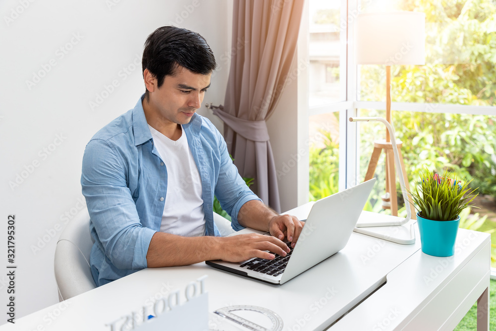 Attractive man is working at home using laptop computer notebook Attractive man is working at home using laptop computer notebook