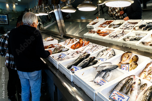 A man in a fish store chooses seafood.freshly caught sea fish or oysters or prawns on ice on a store sail