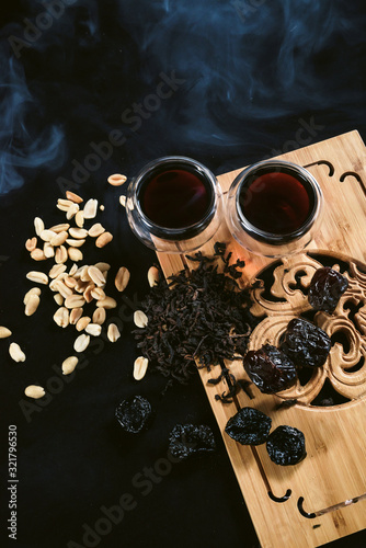 Chinese tea ceremony. Two cups of puer pu erh old aroma tea and snacks - peanut and prunes at tea board © ANR Production