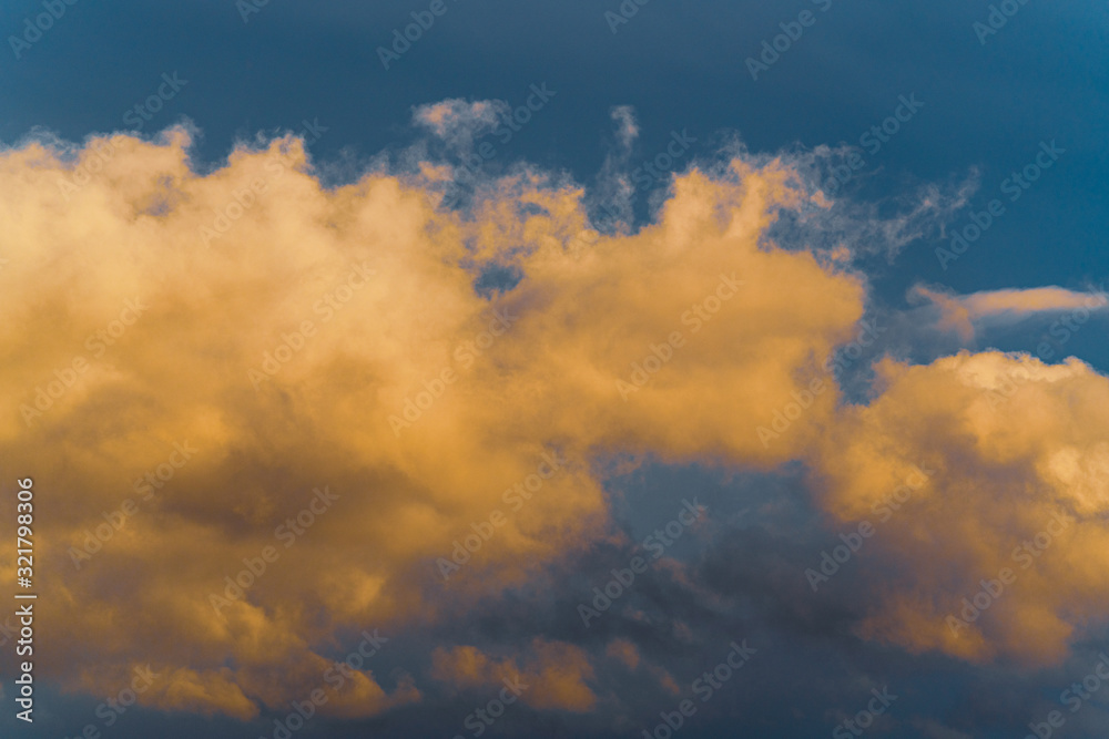 Stunning fluffy thunderstorm clouds illuminated by disappearing rays at sunset and dark cumulonimbus floating across sunny blue sky to change season weather. Natural abstract meteorology background.
