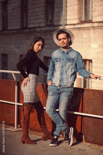 Stylish guy and girl posing in front of the camera on the street.