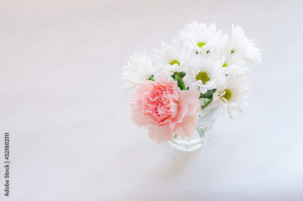 ピンクのカーネーションと白い菊の小さなブーケ トップビュー 左にコピースペース 白背景