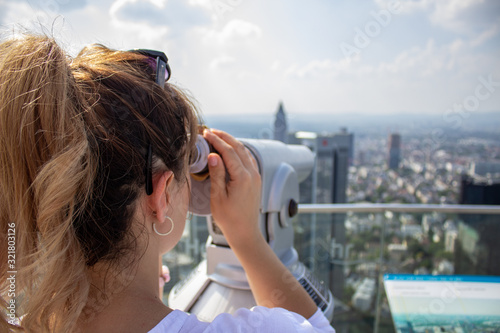 Young tourist girl with looking at the Frankfurt from the top of the main tower. Aerial View Frankfurt am Main from main tower to financial center.