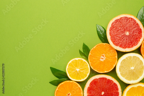 Citruses fruits on green background with copyspace, fruit flatlay, summer minimal compositon with grapefruit, lemon, mandarin and orange