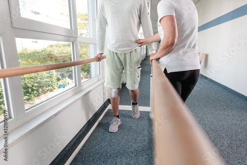 Foto Therapist helping young man learning to walk again in rehabilitation
