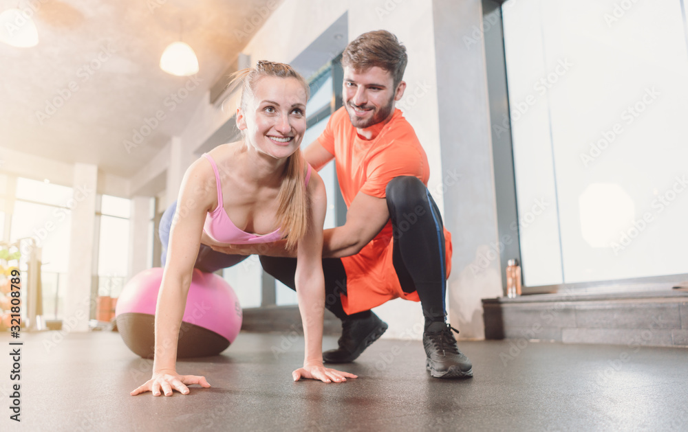Woman with personal trainer in the gym doing pushups Woman with personal trainer in the gym doing pushups