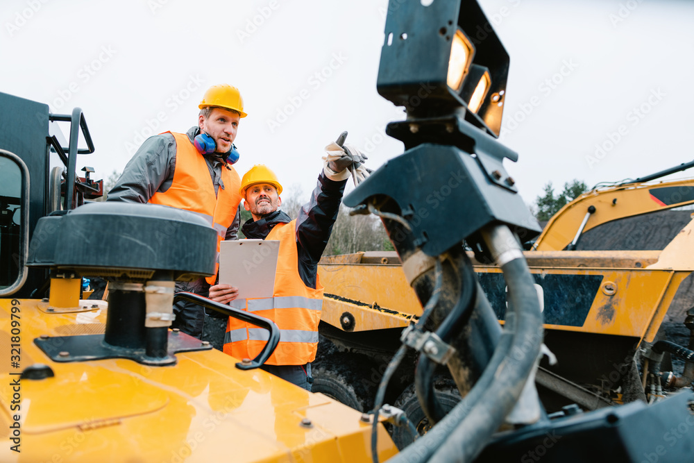 Two male workers on excavator in digging operation or quarry Two male workers on excavator in digging operation or quarry