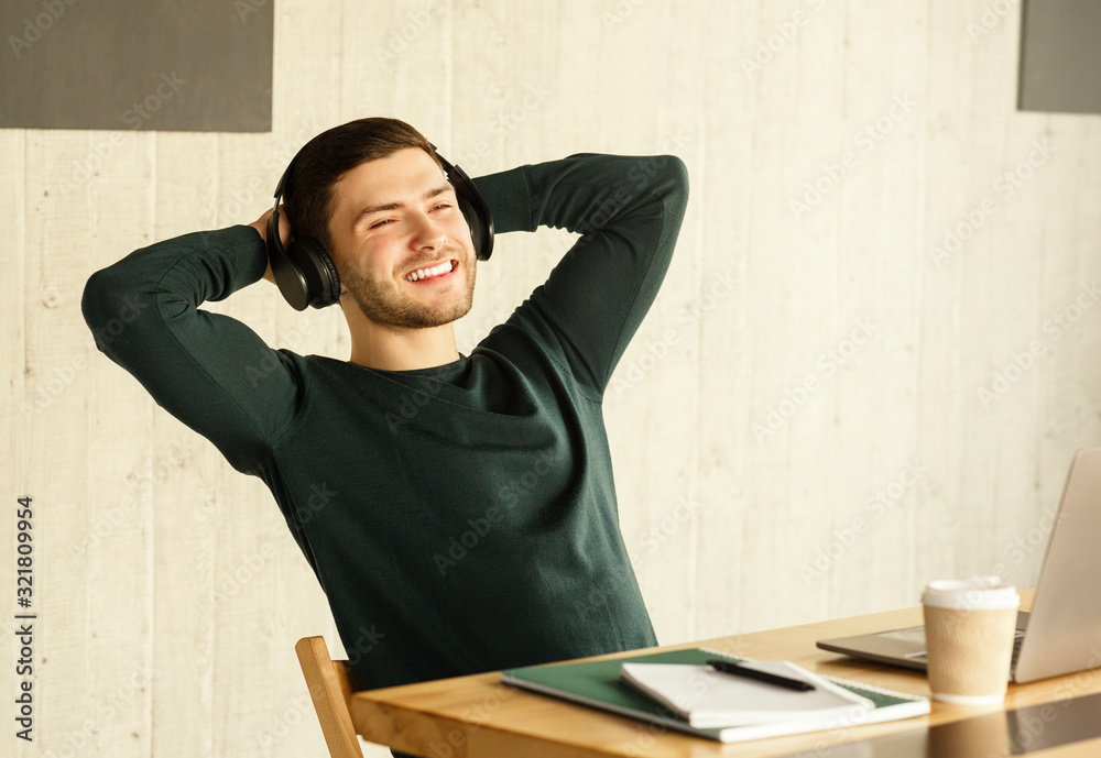 Obraz premium Freelance Guy In Headphones Procrastinating Relaxing Sitting In Modern Office