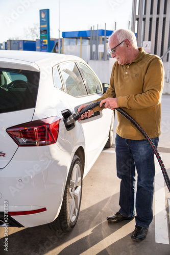 Old man filling up his car with gas.