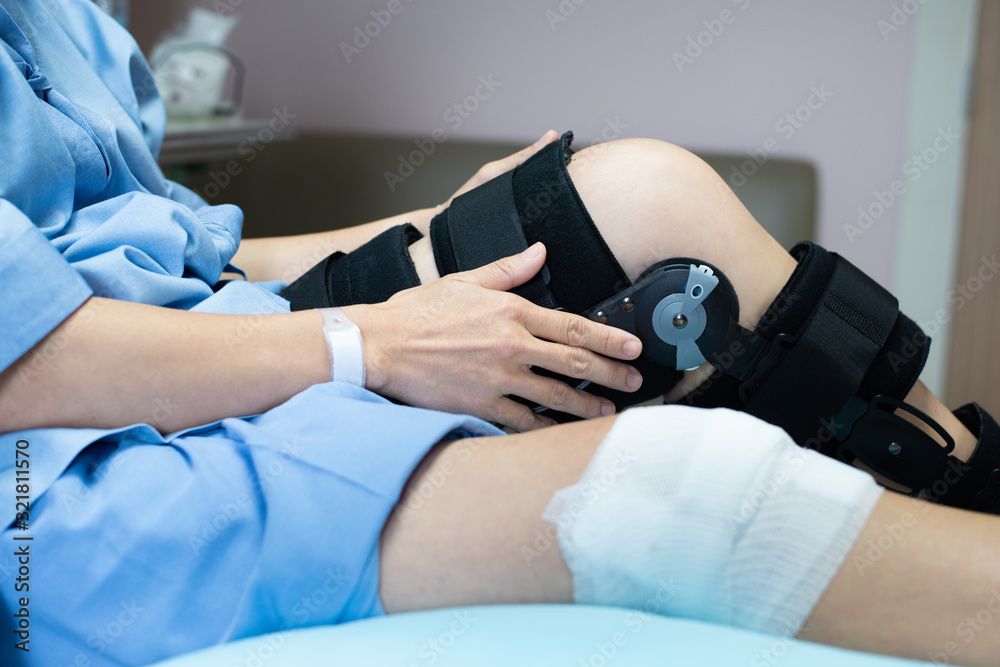 Obraz premium Asian woman patient with bandage compression knee brace support injury on the bed in nursing hospital.healthcare and medical support.