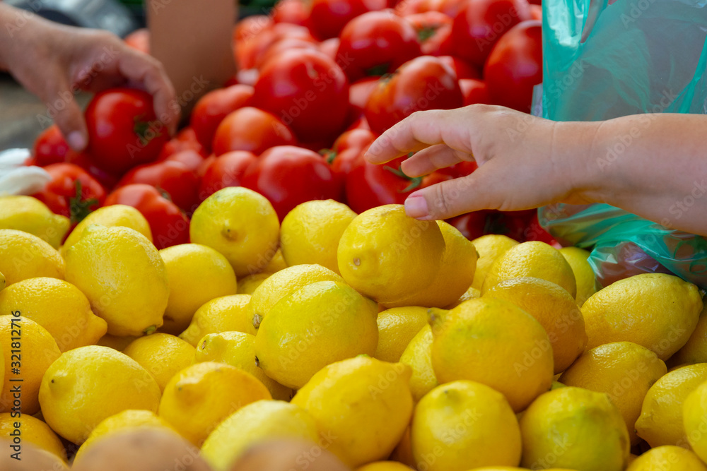 Woman select lemon and tomato on a street market in Greece. Sell local ecological fruits and vegetables, buy local food