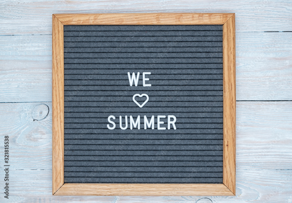 grey felt Board in a wooden frame with the text in English we love summer. heart sign instead of the word love. blank for design.
