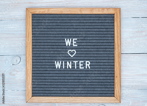 grey felt Board in a wooden frame with the text in English we love winter. heart sign instead of the word love. blank for design.