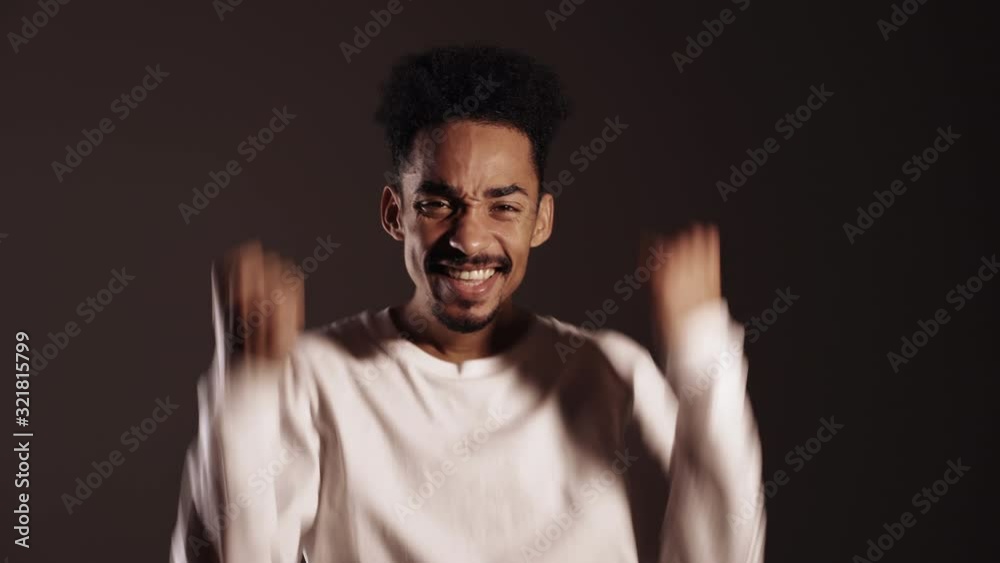 Portrait of happy excited african man in white showing YES sign gesture. Guy succeeded at work. Person isolated on dark background. Portrait of happy excited african man in white showing YES sign gesture. Guy succeeded at work. Person isolated on dark background.