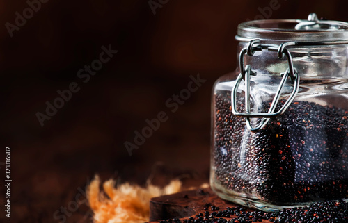 Black quinoa seeds in glass jar, vintage kitchen table background, selective focus