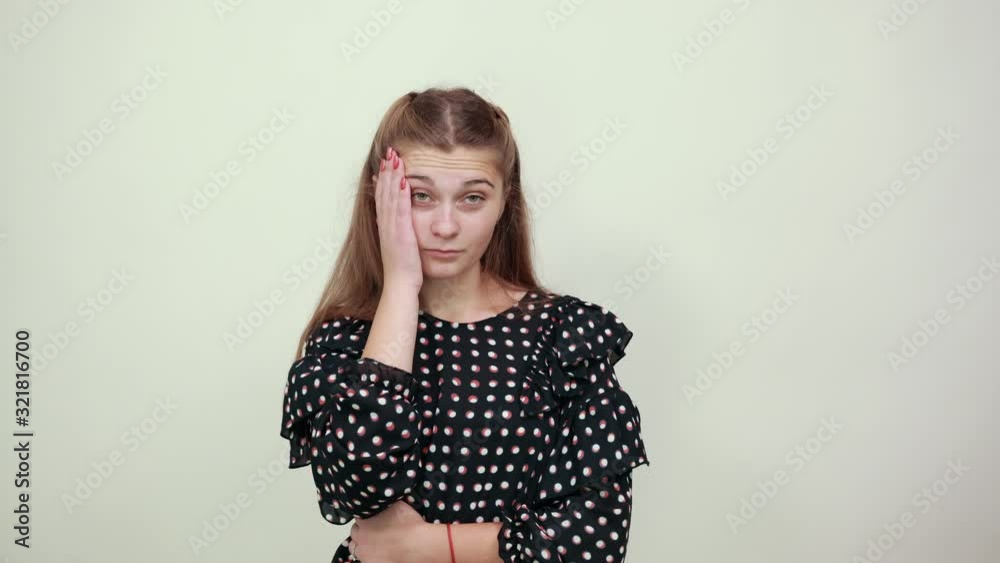 Fair-haired beautiful girl in a black dress with white circles upset girl puts her head on hand and thinks