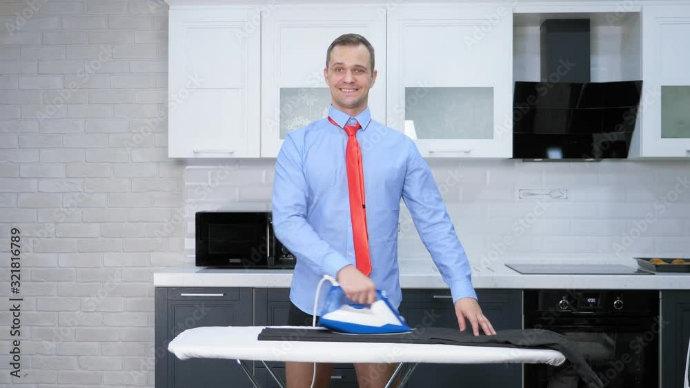vertical shot. handsome man in tie ironing pants . the kitchen of his house vertical shot. handsome man in tie ironing pants . the kitchen of his house