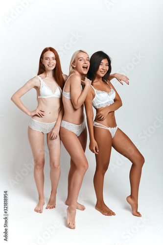 happy awesome Asian  Caucasian girls having fun in the studio with white wall  full length photo. isolated background.shopping  lifestyle 