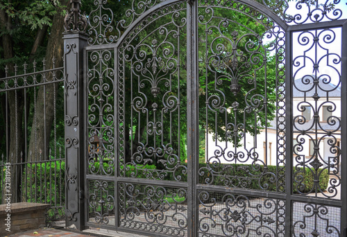 Beautiful forged cast iron grille. The stylish landscape is surrounded by summer greenery. Architecture elements