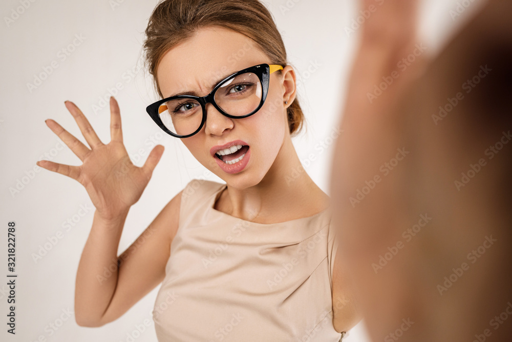 Portrait of angry woman wearing glasses gives a slap in the face. girl hits the camera